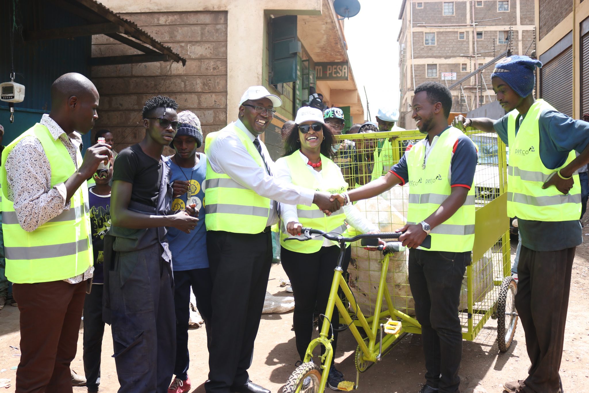 Mrs. Joyce Waweru (in sun glasses), PETCO Country Program Manager hands over innovative plastic bottle collecting bicycles to youth in Nairobi's informal estates