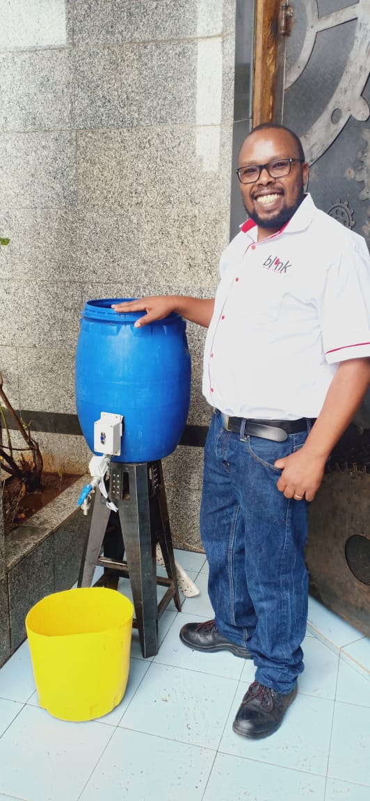 Peter Mbari displays his wash station