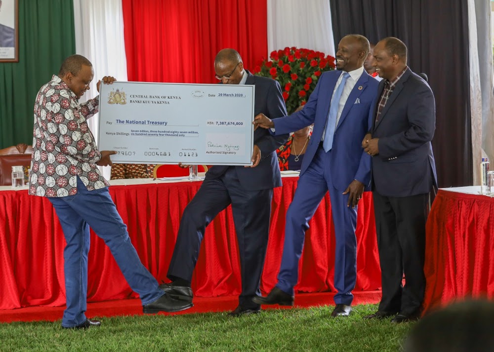 President Kenyatta holds a cheque from the Governor CBK at