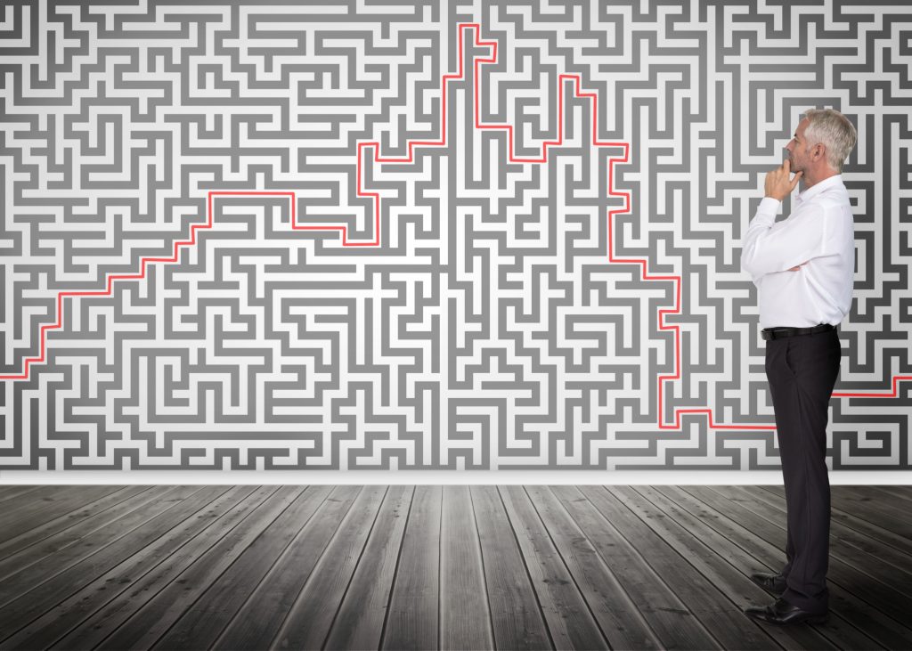 Thoughtful businessman looking at a maze on a wall